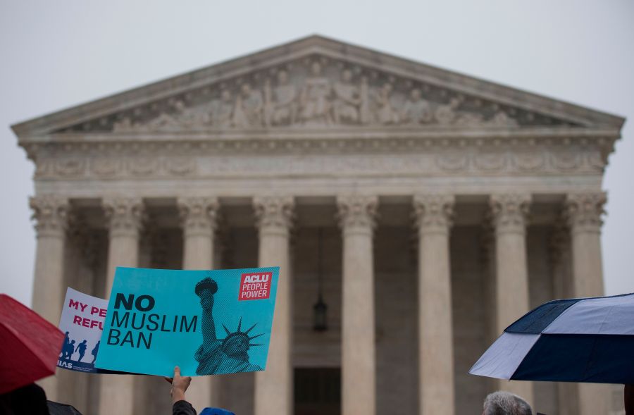 Activists rally against President Donald Trump's travel ban on April 25, 2018 — the day the Supreme Court heard arguments in Hawaii v. Trump — in front of the court in Washington, DC. (Credit: ANDREW CABALLERO-REYNOLDS / AFP / Getty Images)