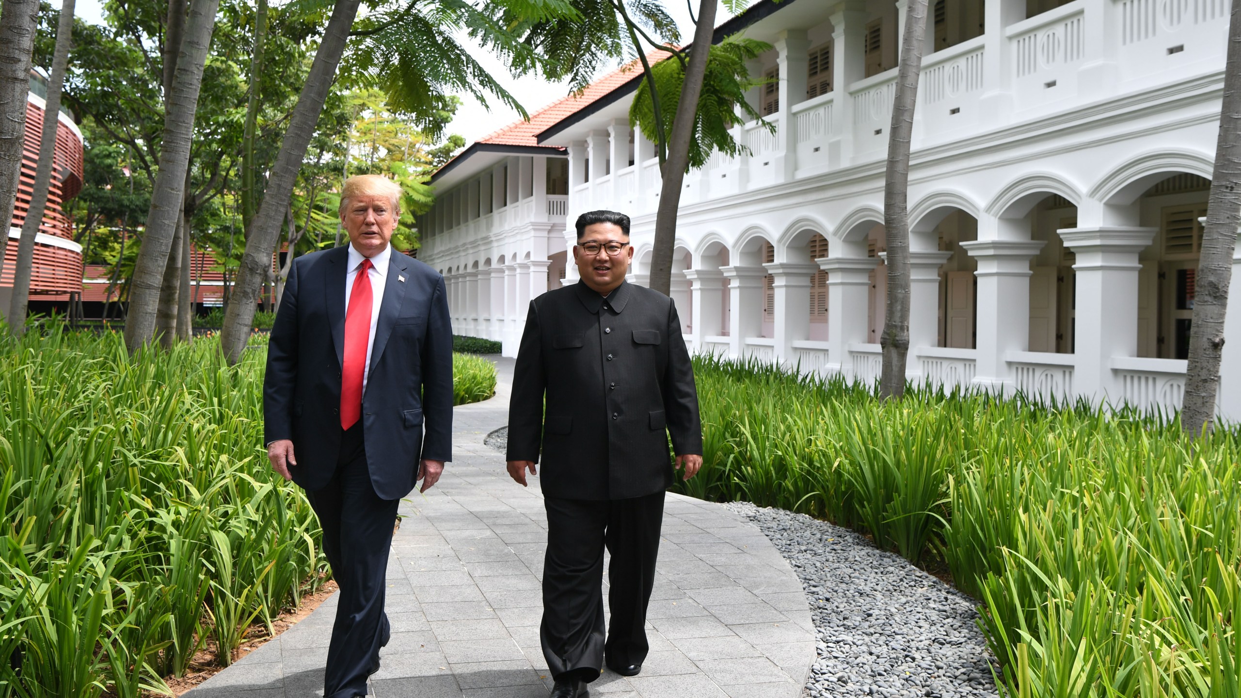 North Korea's leader Kim Jong Un, right, walks with President Donald Trump, left, during a break in talks at their historic US-North Korea summit, at the Capella Hotel on Sentosa island in Singapore on June 12, 2018. (Credit: ANTHONY WALLACE/AFP/Getty Images)