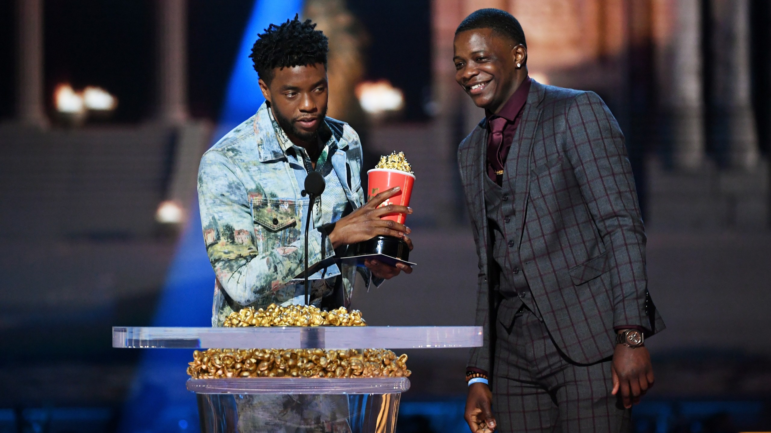 Actor Chadwick Boseman, winner of the Best Hero award for his role in "Black Panther," presents his trophy to James Shaw Jr. onstage during the 2018 MTV Movie And TV Awards at Barker Hangar on June 16, 2018, in Santa Monica. (Credit: Kevin Winter/Getty Images for MTV)