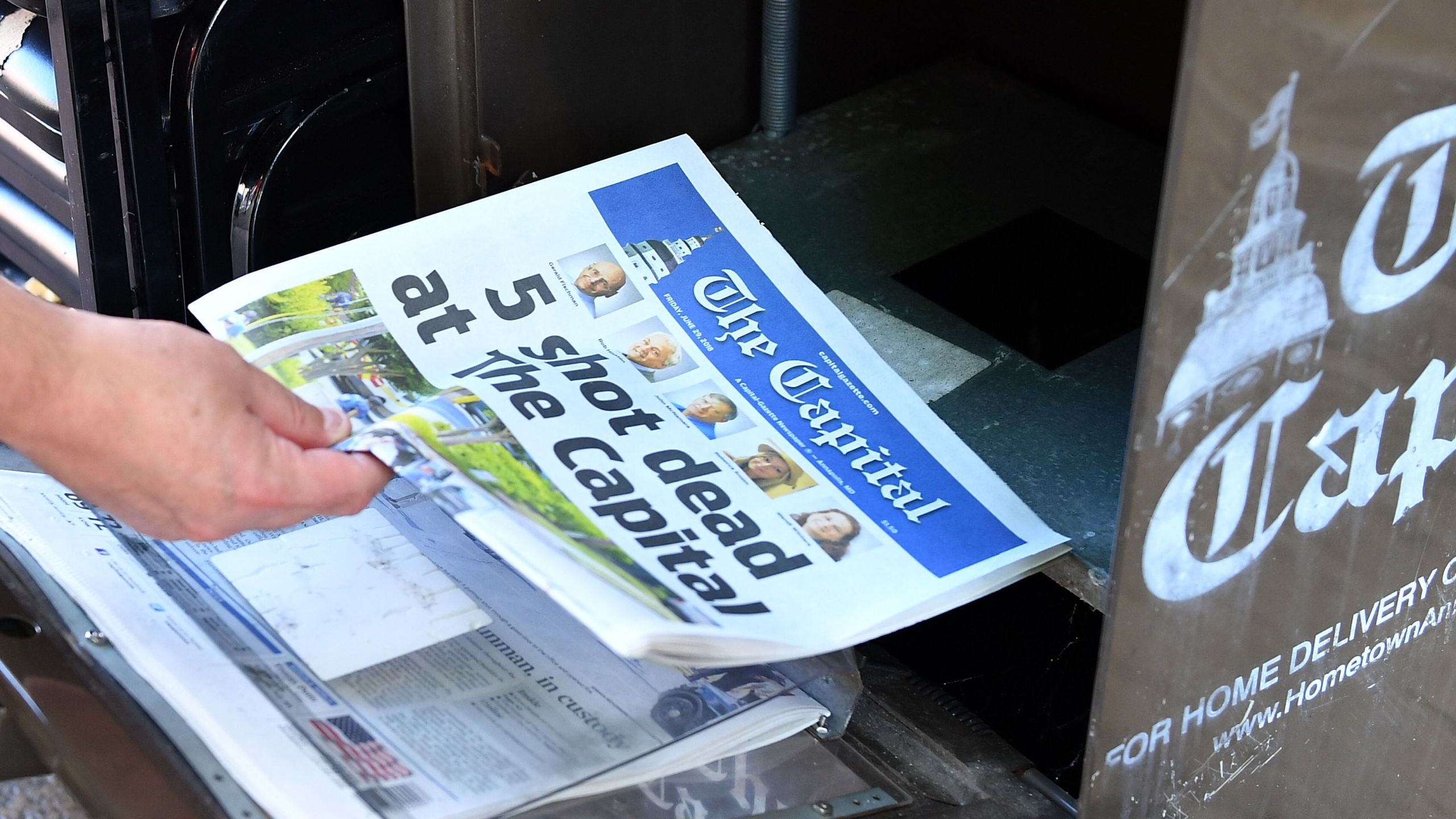 A reporter buys a Capital Gazette newspaper on June 29, 2018, in Annapolis, Maryland, a day after a gunman five people at the publication's office. (Credit: MANDEL NGAN/AFP/Getty Images)