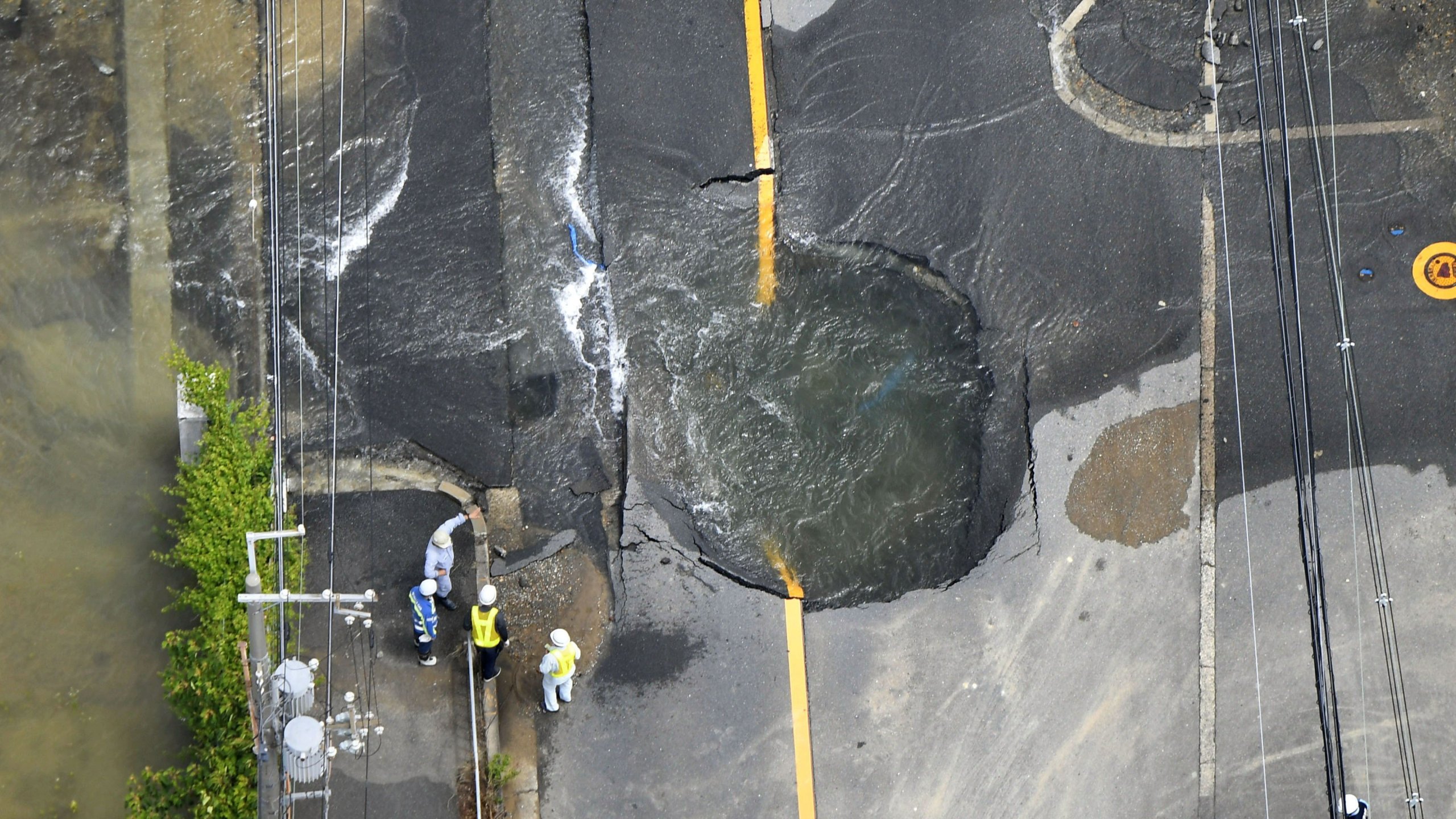 Water floods out from a crack in the road, following the Osaka quake that killed three people in Japan on June 18, 2018. (Credit: AP via CNN)