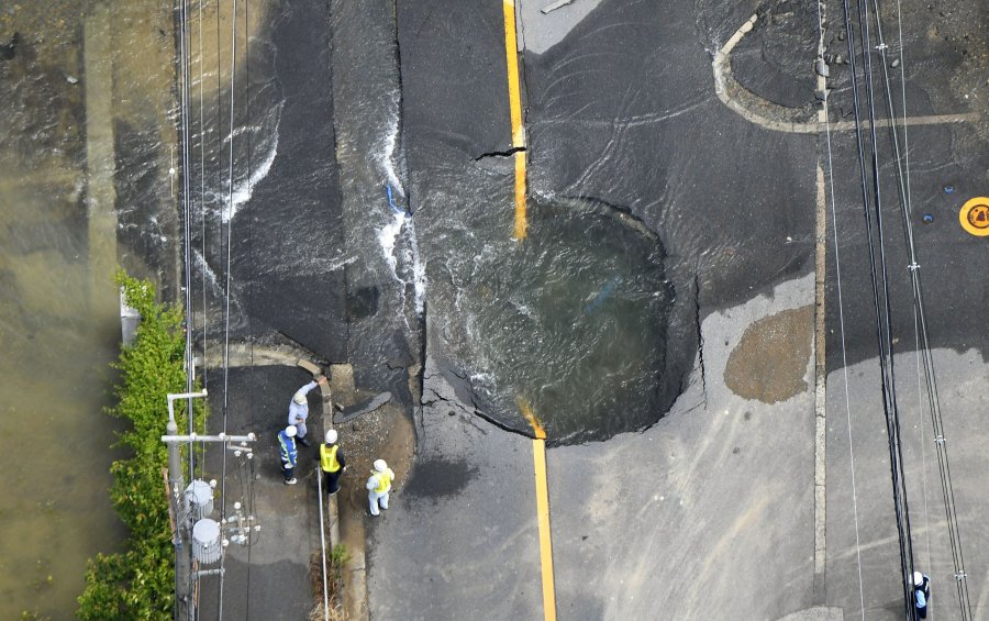 Water floods out from a crack in the road, following the Osaka quake that killed three people in Japan on June 18, 2018. (Credit: AP via CNN)