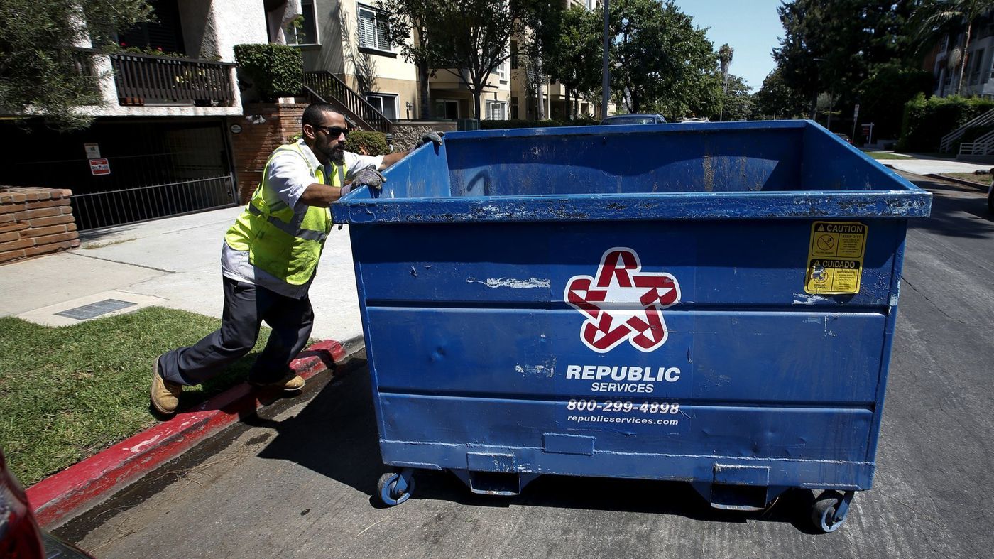 An employee with the waste hauling company Athens Services moves a trash bin in West Los Angeles in 2017. (Credit: Mel Melcon / Los Angeles Times)