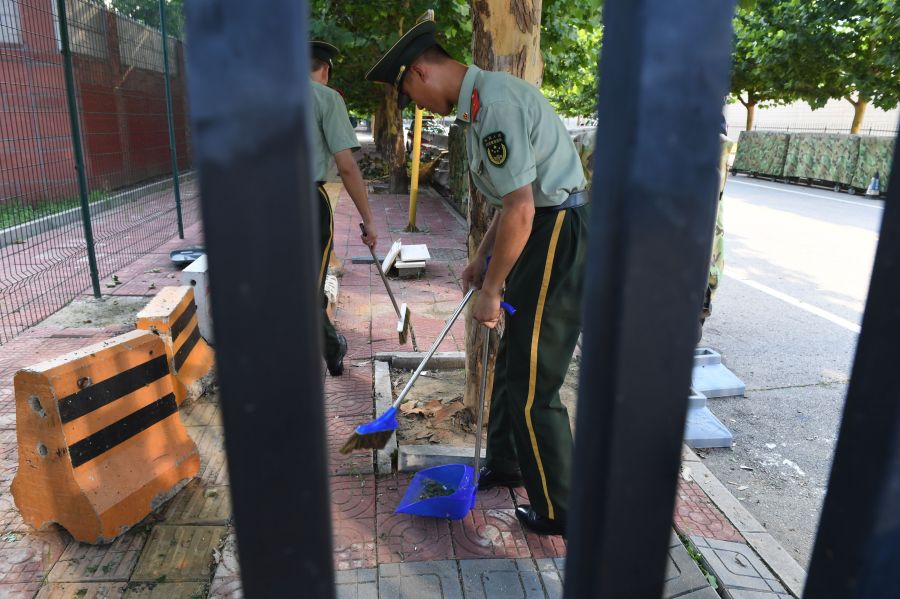 Chinese paramilitary police clean up broken glass and debris outside the US embassy compound in Beijing on July 26, 2018 following a blast near the embassy premises. (Credit: GREG BAKER/AFP/Getty Images)