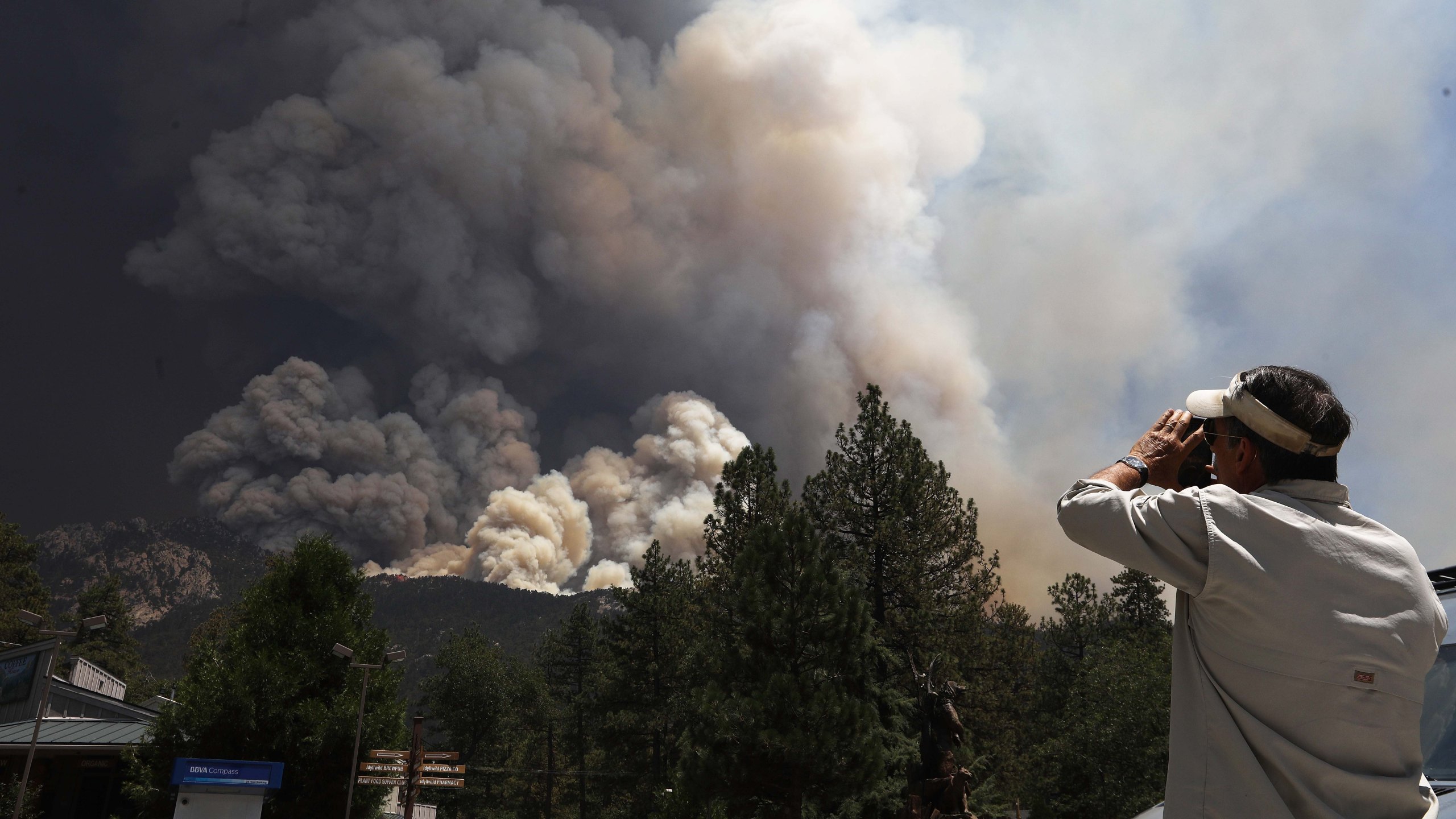 The Cranston Fire burns as a man takes photos near Idyllwild on July 26, 2018. (Credit: Mario Tama / Getty Images)