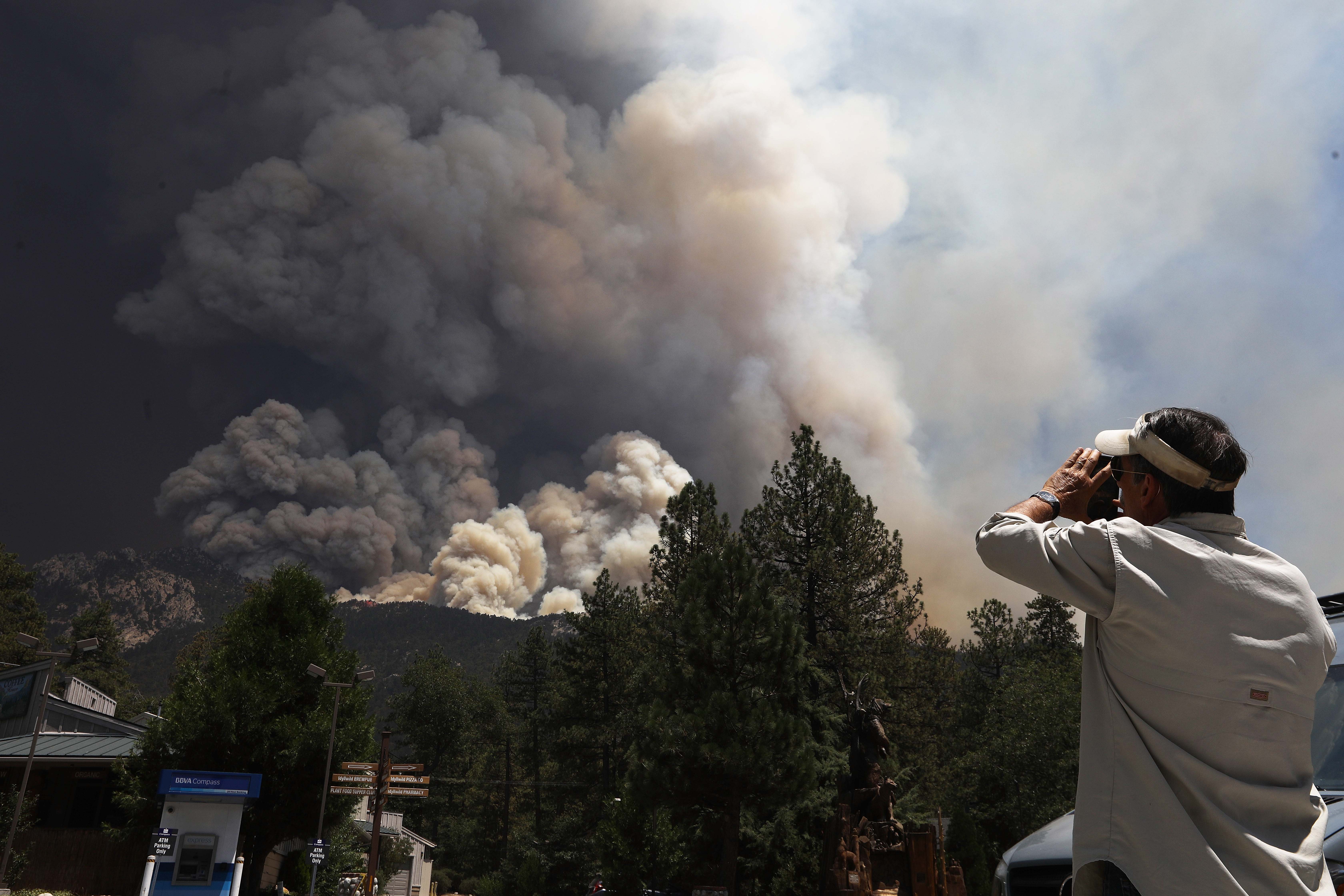 The Cranston Fire burns as a man takes photos near Idyllwild on July 26, 2018. (Credit: Mario Tama / Getty Images)