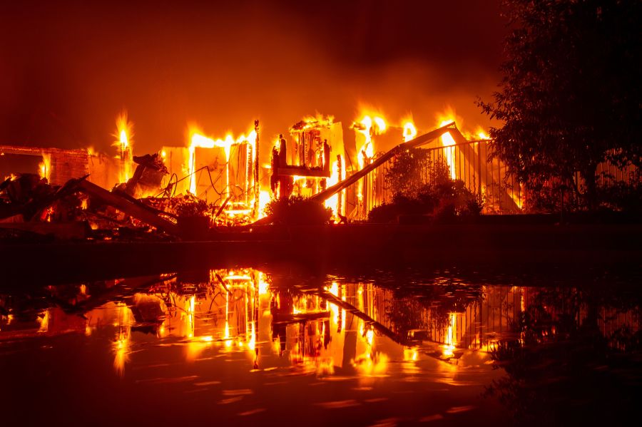 A burning home is reflected in a pool during the Carr Fire in Redding on July 27, 2018. The fire has burned over 44,000 acres and is just 3 percent contained as of Friday morning. (Credit: JOSH EDELSON/AFP/Getty Images)