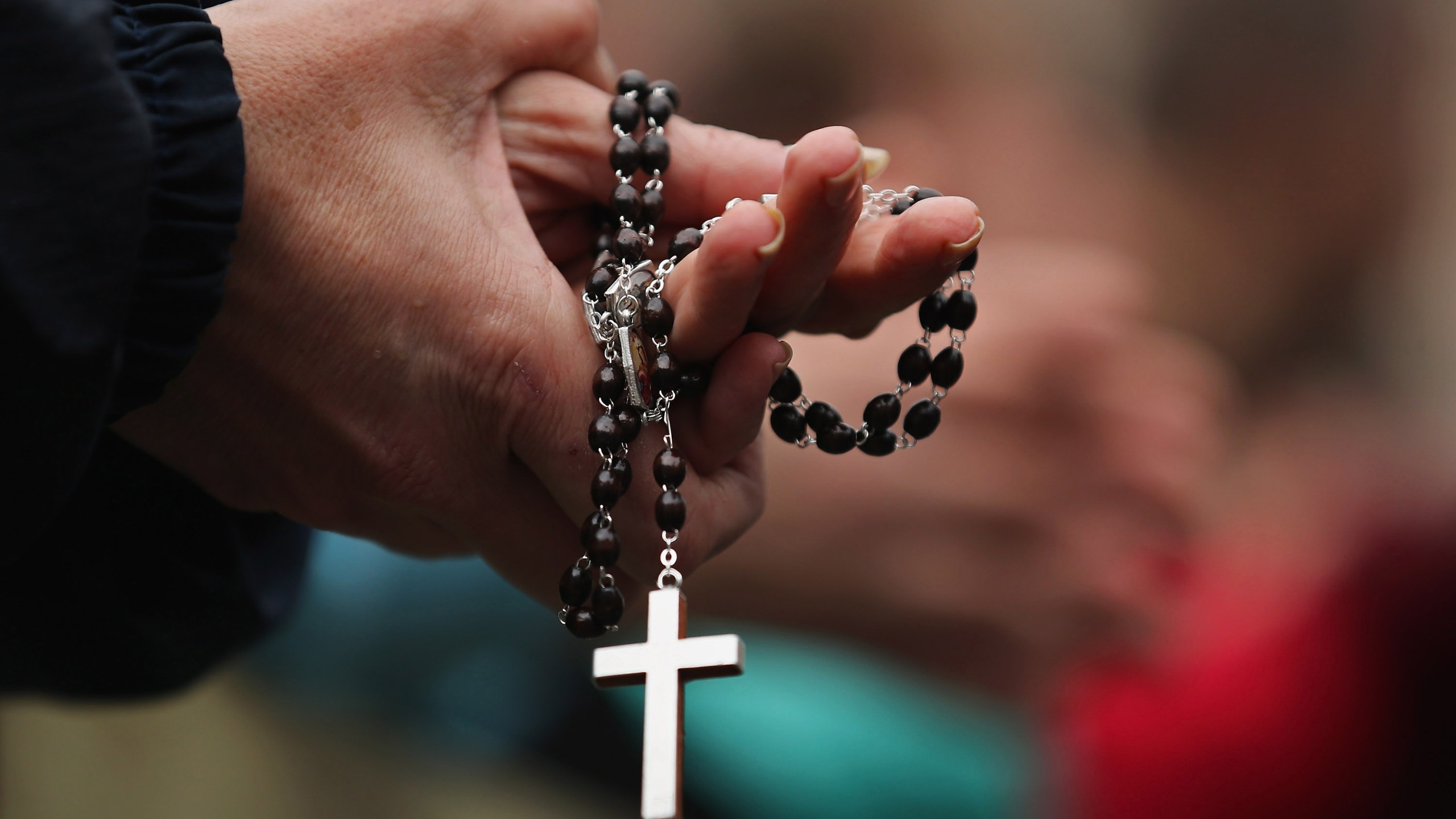 A woman holds rosary beads while she prays and waits for smoke to emanate from the chimney on the roof of the Sistine Chapel on March 13, 2013, in Vatican City. (Credit: Dan Kitwood / Getty Images)