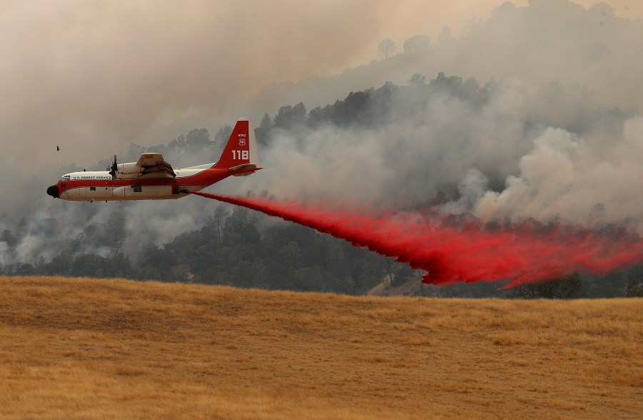 A firefighting air tanker drops Foscheck fire retardant on a hillside ahead of the County Fire on July 2, 2018 in Esparto, California. (Credit: Justin Sullivan/Getty Images)