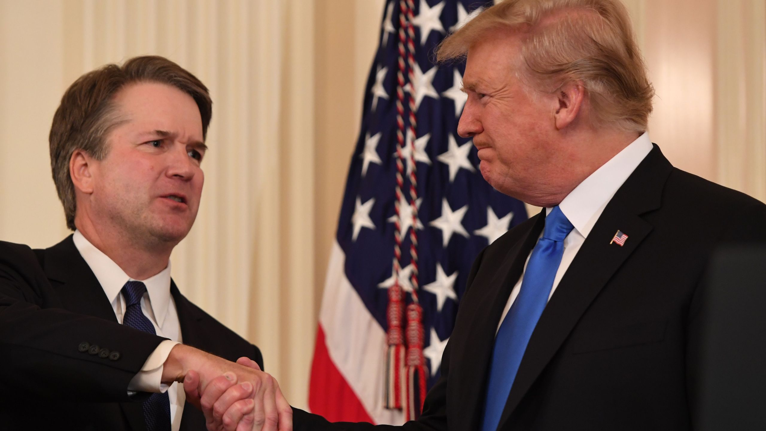 Judge Brett Kavanaugh, left, shakes hands with President Donald Trump after being nominated to the Supreme Court in the East Room of the White House on July 9, 2018. (Credit: Saul Loeb / AFP / Getty Images)