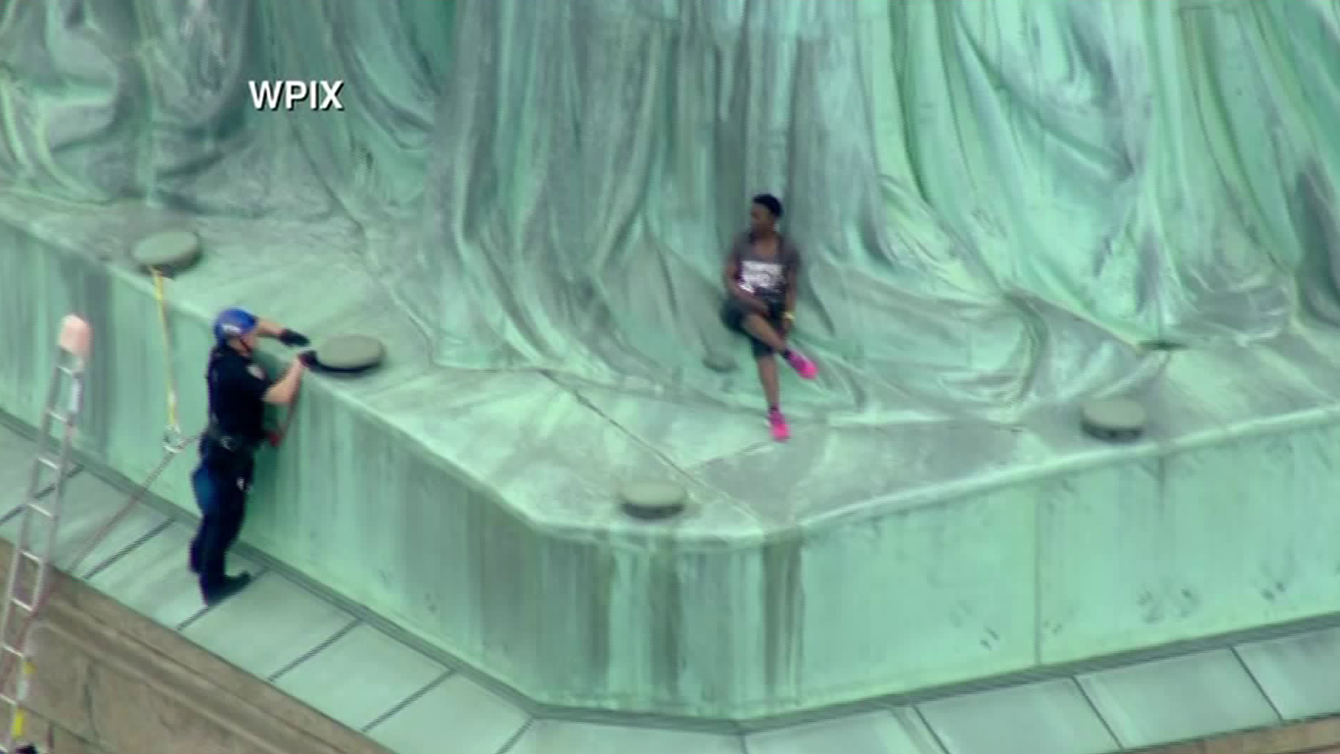 A law enforcement official speaks with a woman who climbed the base of the Statue of Liberty in New York on July 4, 2018. (Credit: WPIX via CNN)