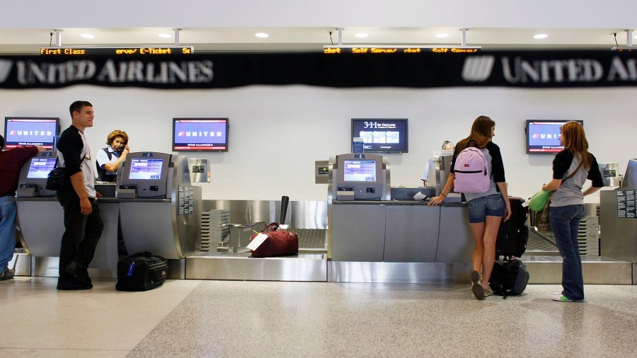 In this file photo, passengers check in with their baggage at the United Airlines counter at the Miami International Airport in Miami. (Credit: Joe Raedle/Getty Images)