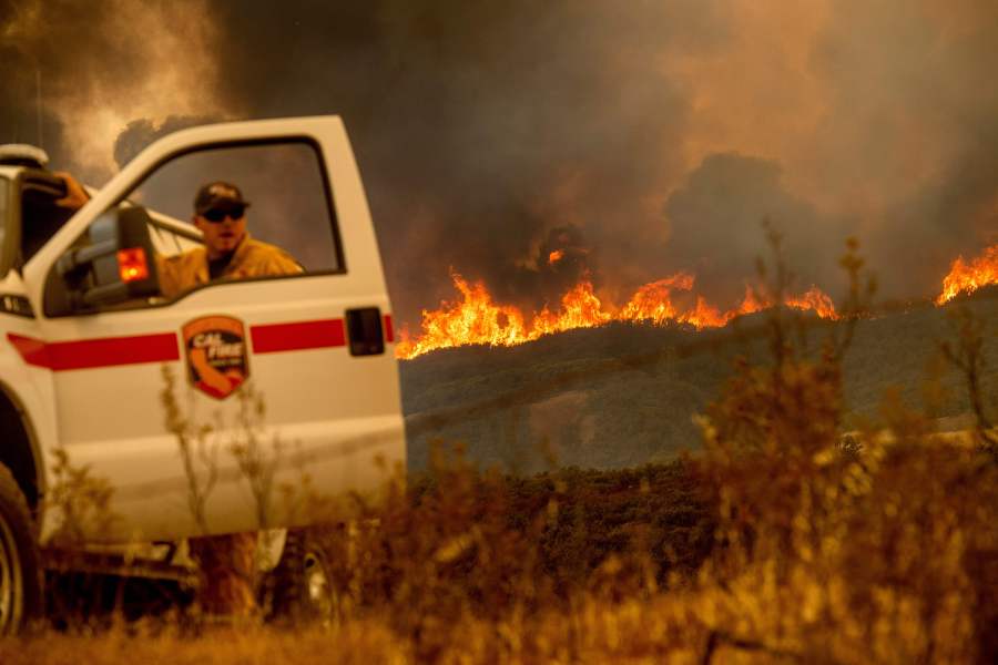 The Ranch Fire, part of the Mendocino Complex Fire, crests a ridge as Cal Fire Battalion Chief Matt Sully directs firefighting operations near Clearlake Oaks on Aug. 5, 2018. (Credit: Noah Berger / AFP / Getty Images)