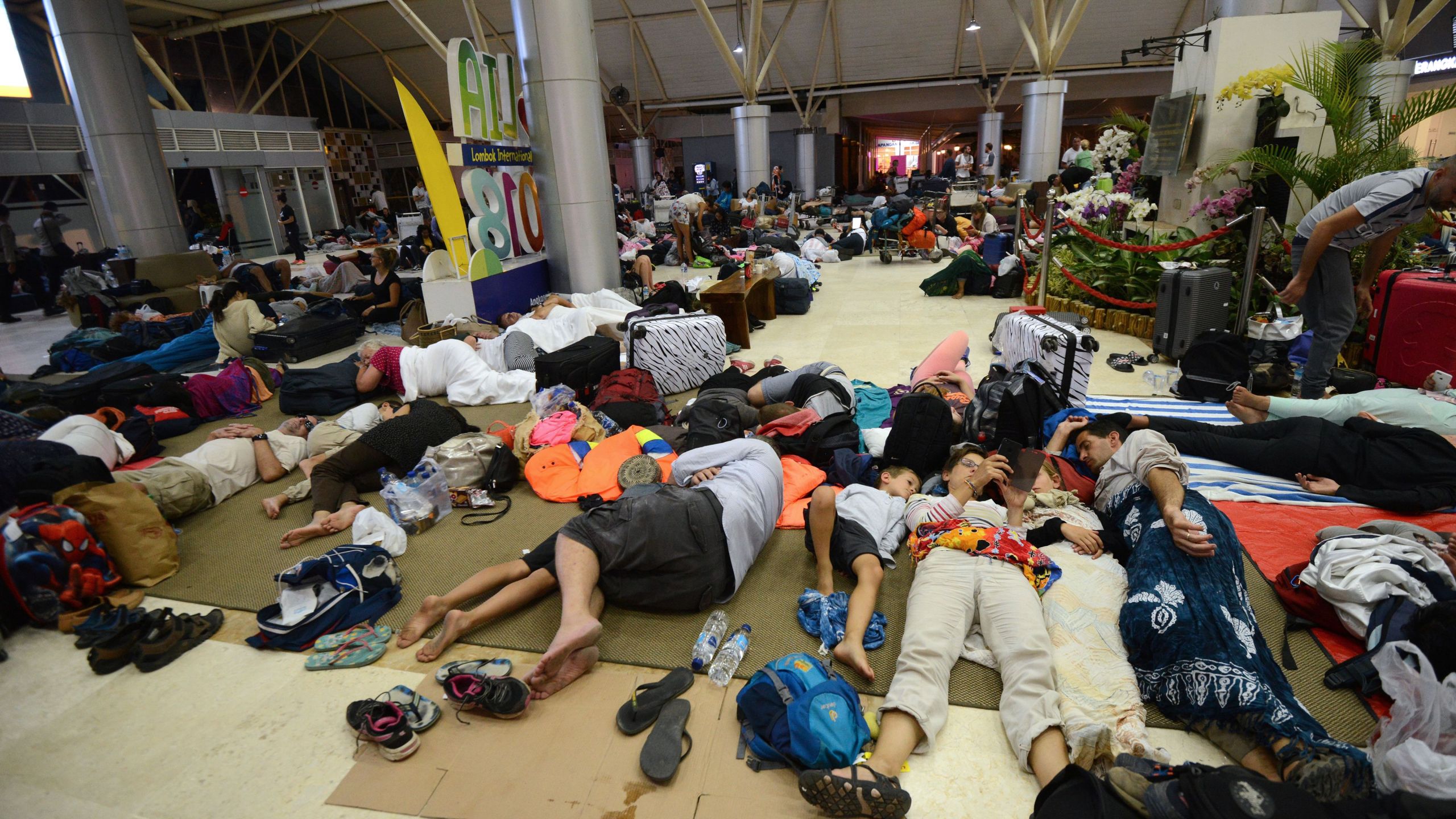 Tourists sleep while waiting to depart from the Praya Lombok International Airport on the West Nusa Tenggara province on Aug. 6, 2018. (Credit: SONNY TUMBELAKA/AFP/Getty Images)