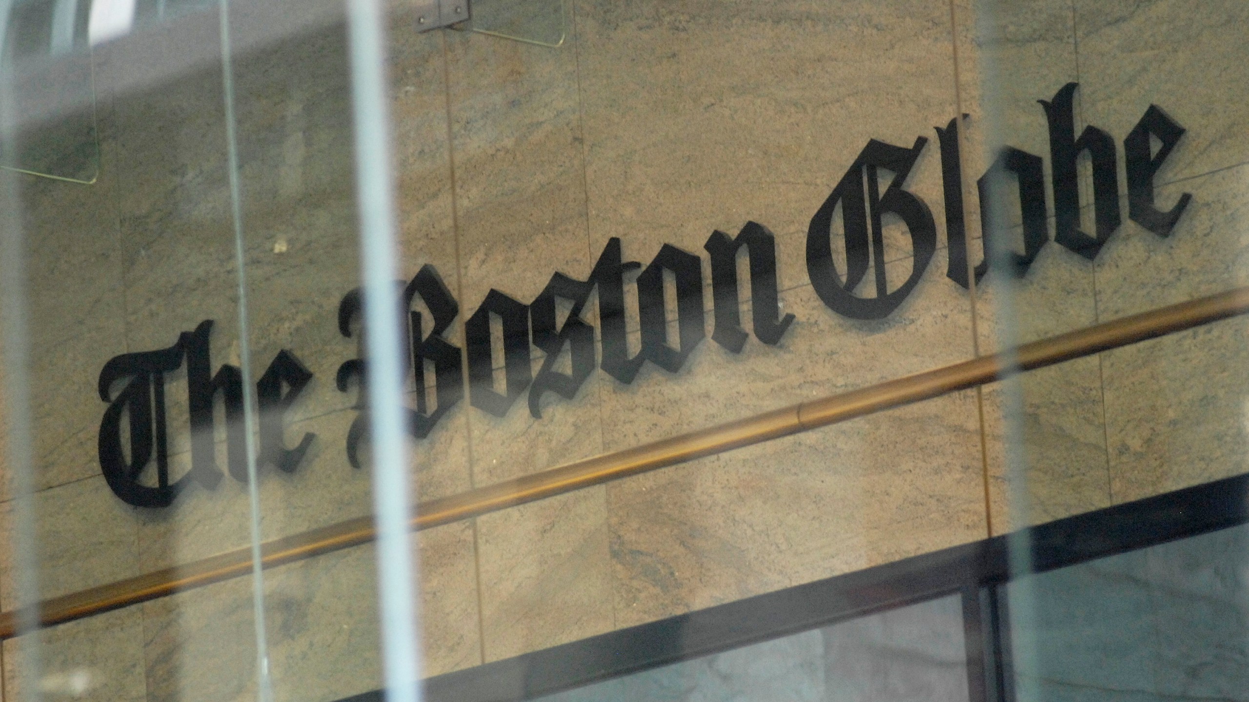 The Boston Globe logo as seen through the windows across from the new location of the Boston Globe at 53 State Street, Boston, at one Exchange Place in the Exchange Building on August 15, 2018. - Branded "enemy of the people" by us President Donald Trump, the US news media is responding with a campaign aimed at countering the president's narrative and highlighting the importance of a free press. More than 200 news organizations are to participate in a coordinated campaign on August 16, 2018, with editorials about the importance of an independent media and a social media hashtag #EnemyOfNone. The move comes in response to a call by the Boston Globe amid a growing sense of unease that Trump's rhetoric is harmful to a free press and may even incite violence against journalists. (Photo by Joseph PREZIOSO / AFP) (Photo credit should read JOSEPH PREZIOSO/AFP/Getty Images)