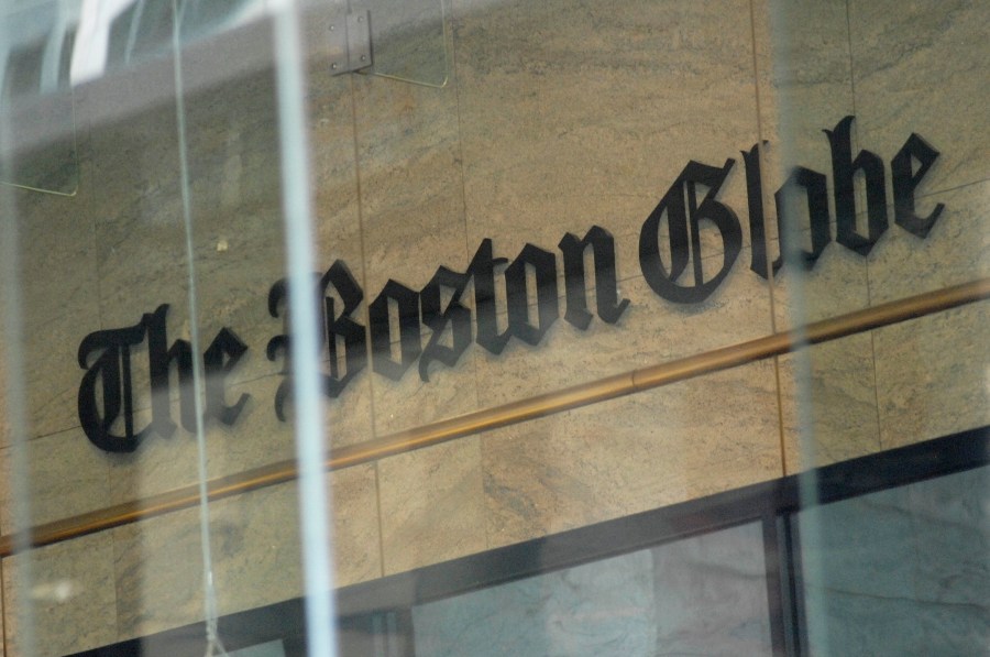 The Boston Globe logo as seen through the windows across from the new location of the Boston Globe at 53 State Street, Boston, at one Exchange Place in the Exchange Building on August 15, 2018. - Branded "enemy of the people" by us President Donald Trump, the US news media is responding with a campaign aimed at countering the president's narrative and highlighting the importance of a free press. More than 200 news organizations are to participate in a coordinated campaign on August 16, 2018, with editorials about the importance of an independent media and a social media hashtag #EnemyOfNone. The move comes in response to a call by the Boston Globe amid a growing sense of unease that Trump's rhetoric is harmful to a free press and may even incite violence against journalists. (Photo by Joseph PREZIOSO / AFP) (Photo credit should read JOSEPH PREZIOSO/AFP/Getty Images)