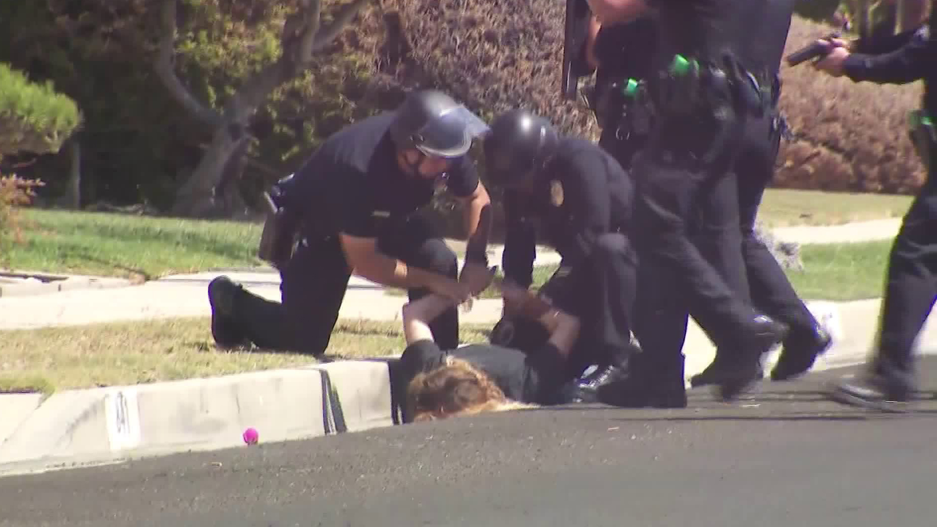 A woman is detained outside a home in the Harbor Gateway neighborhood in connection with a homicide investigation on Sept. 12, 2018. (KTLA)