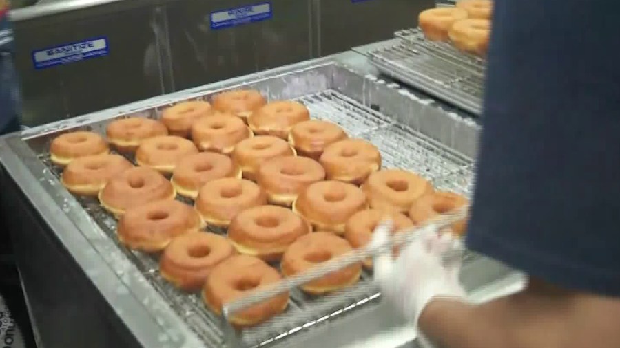 An employee at Randy's Donuts cooks up some doughnuts during the iconic eatery's opening of a new store in El Segundo on Sept. 10, 2018. (Credit: KTLA)