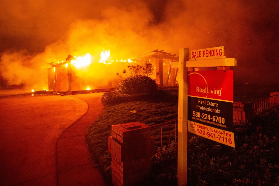 A real estate sign is seen in front of a burning home in Redding during the Carr Fire on July 27, 2018. (Credit: Josh Edelson / AFP / Getty Images)