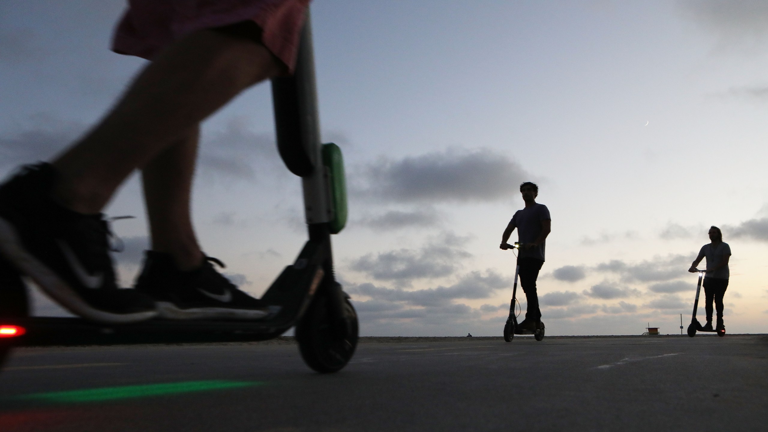 People ride shared dockless electric scooters along Venice Beach on Aug. 13, 2018. (Credit: Mario Tama/Getty Images)