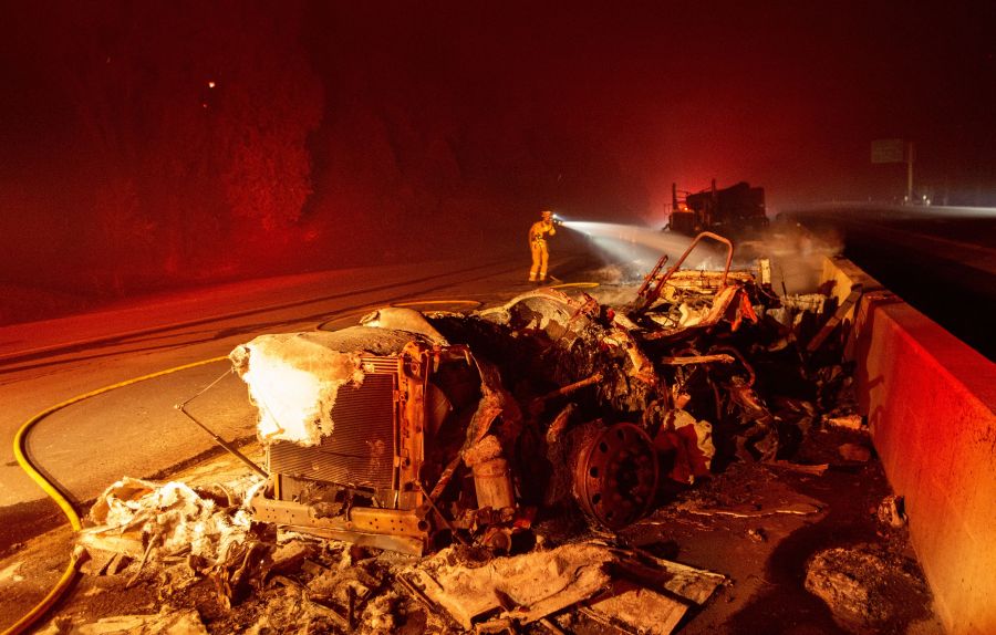 A firefighter sprays down a burned big rig truck that was abandoned along Interstate 5 as the Delta Fire tore through the region in Delta on Sept. 5, 2018. (JOSH EDELSON/AFP/Getty Images)