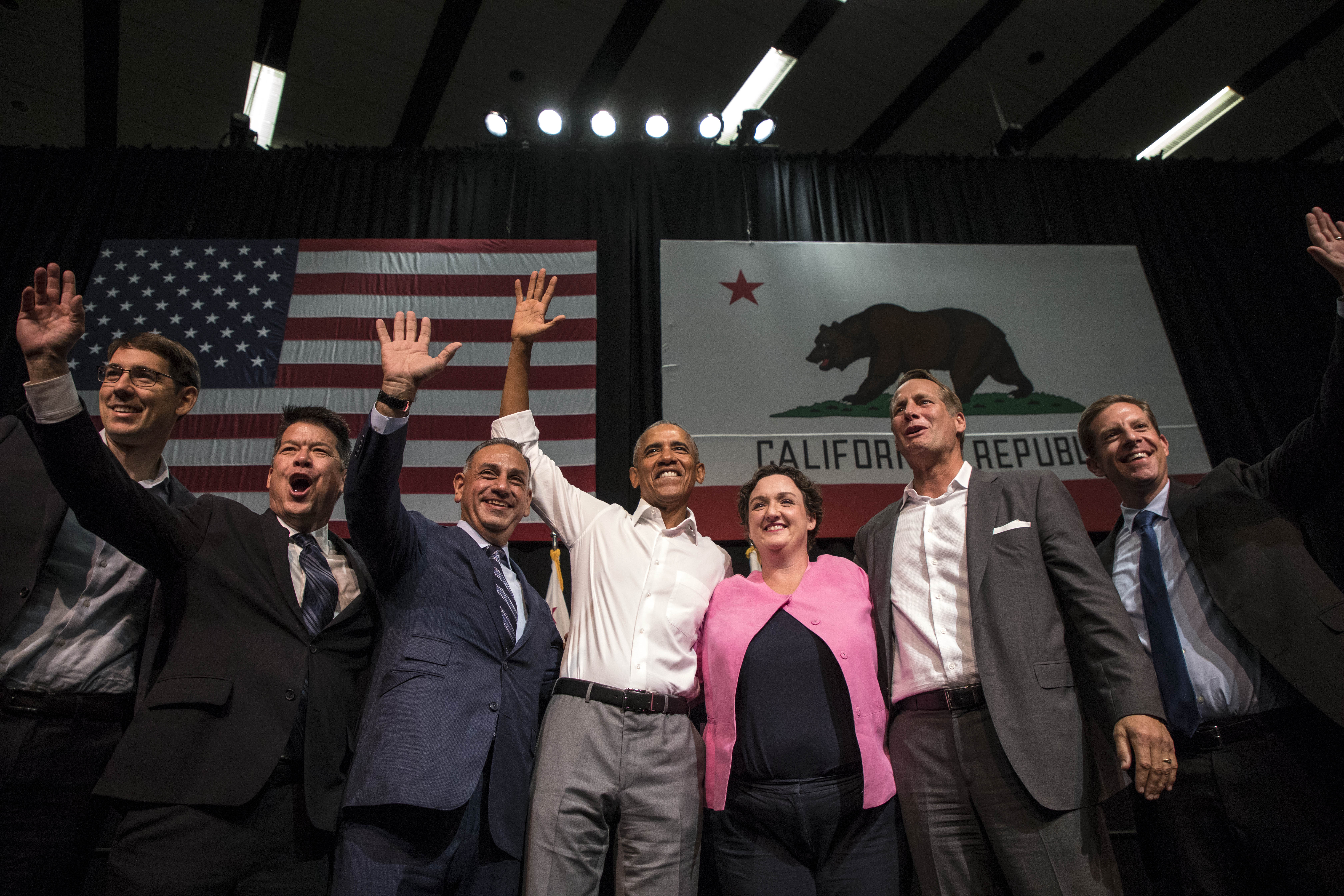 From left to right, Josh Harder, TJ Cox, Gil Cisneros, former U.S. President Barack Obama, Katie Porter, Harley Rouda, and Mike Levin wave to supporters during a congressional candidates rally at the Anaheim Convention Center on Sept. 8, 2018. (Credit: Barbara Davidson/Getty Images)