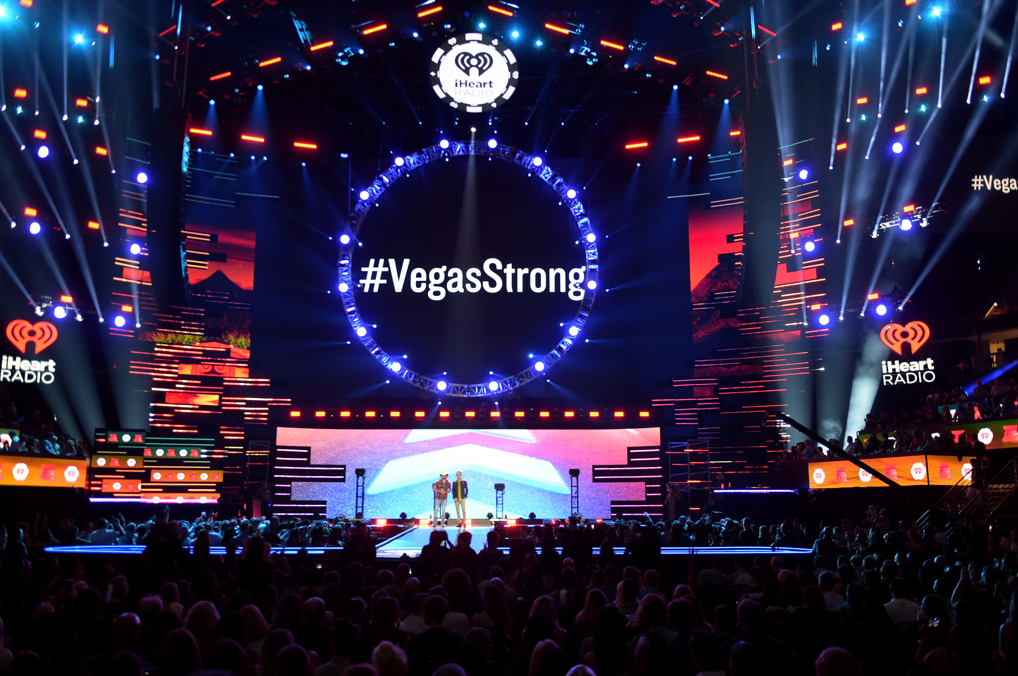 '#VegasStrong' is projected on a video screen while Jason Aldean (L) and Bobby Bones speak onstage during the 2018 iHeartRadio Music Festival at T-Mobile Arena on September 21, 2018 in Las Vegas, Nevada. (Credit: Kevin Winter/Getty Images for iHeartMedia)