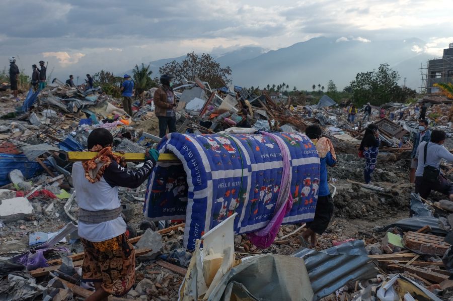 Residents walk trough debris in Petobo, Indonesia's Central Sulawesi on Oct 6, 2018, following a devastating earthquake and tsunami. (Credit: YUSUF WAHIL/AFP/Getty Images)