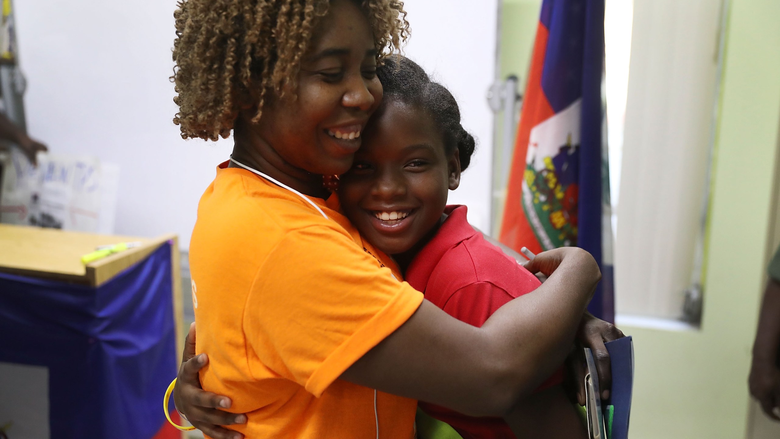 Santcha Etienne, left, hugs Ronyde Christina Ponthieux, 10, after she spoke about her father, originally from Haiti, who is here under Temporary Protective Status during a press conference on Nov. 6, 2017, in Miami, Florida. (Credit: Joe Raedle / Getty Images)