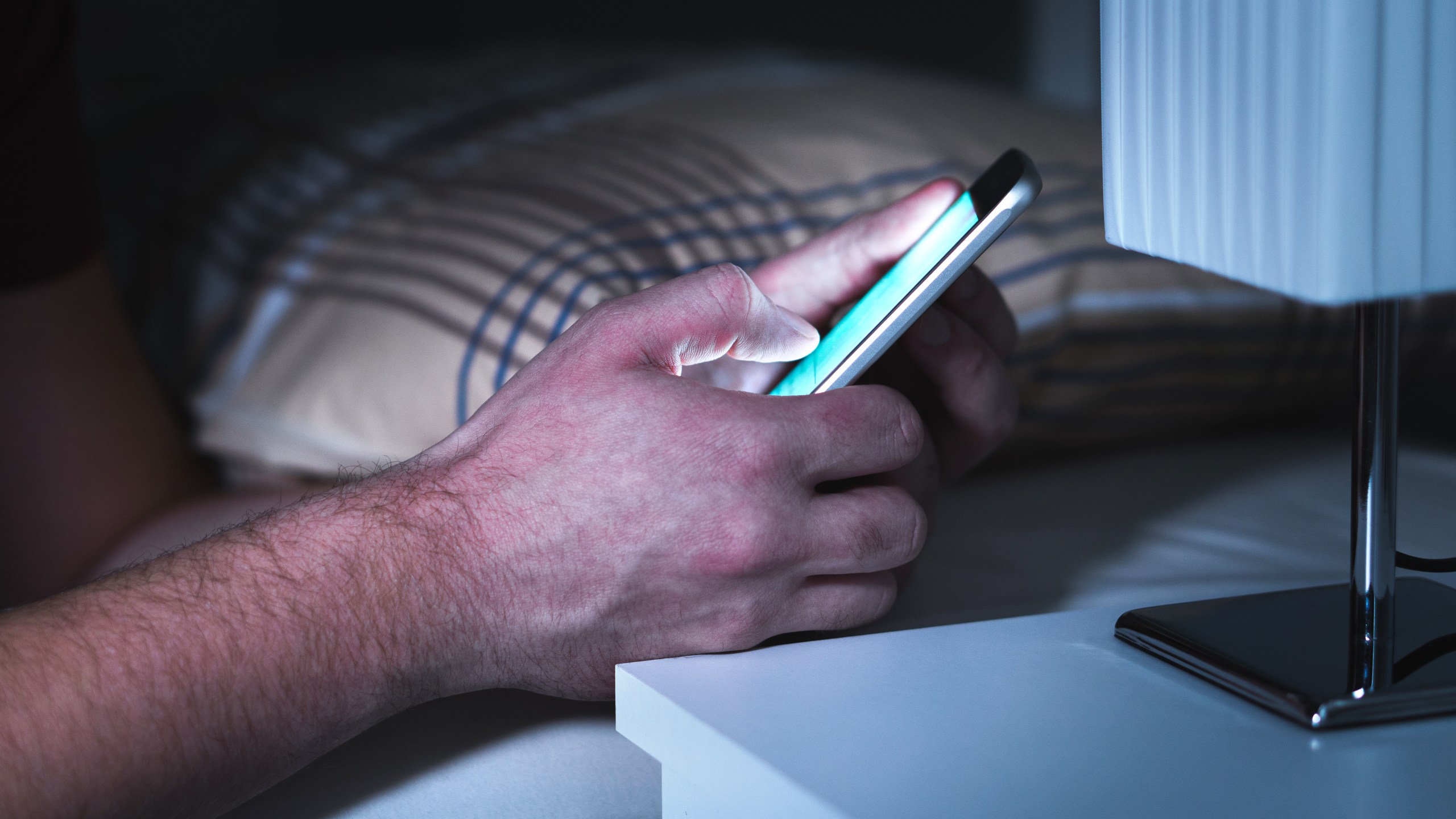 A man uses a smartphone in bed in a file image. (Credit: iStock / Getty Images Plus)