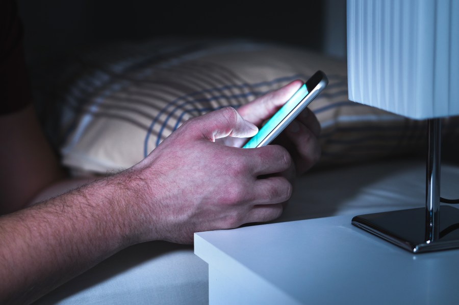 A man uses a smartphone in bed in a file image. (Credit: iStock / Getty Images Plus)