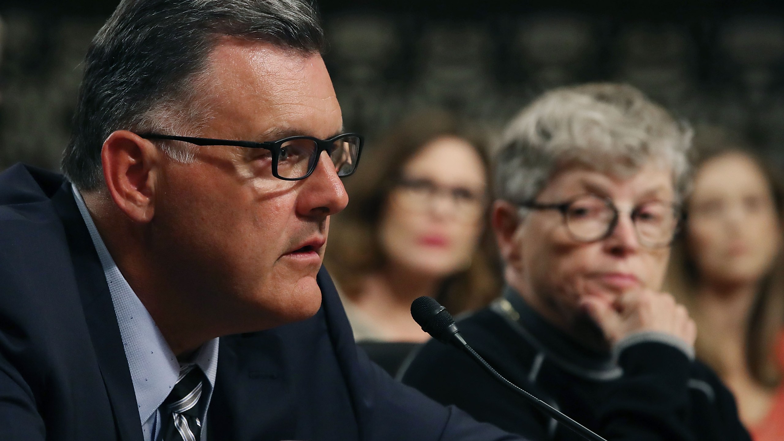 Steve Penny, former president of USA Gymnastics, pleads the Fifth, while seated next to Lou Anna Simon, right, former president of Michigan State University, during a Senate committee hearing on June 5, 2018. (Credit: Mark Wilson / Getty Images)