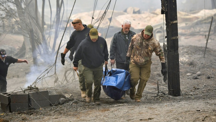 Yuba and Butte County Sheriff officers carry a body away from a burned residence in Paradise on November 10, 2018. (Credit: JOSH EDELSON/AFP/Getty Images)