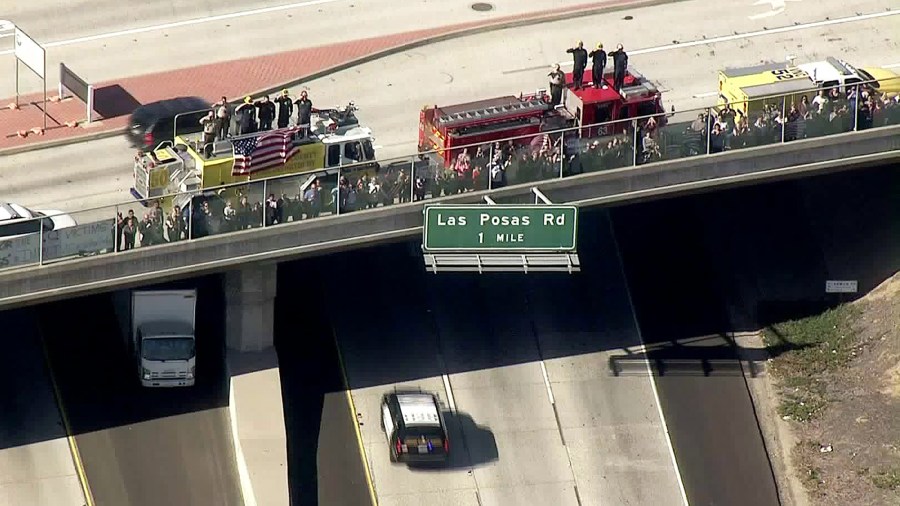 Emergency personnel salute as the procession for Sgt. Ron Helus passes below on Nov. 8, 2018. (Credit: KTLA)