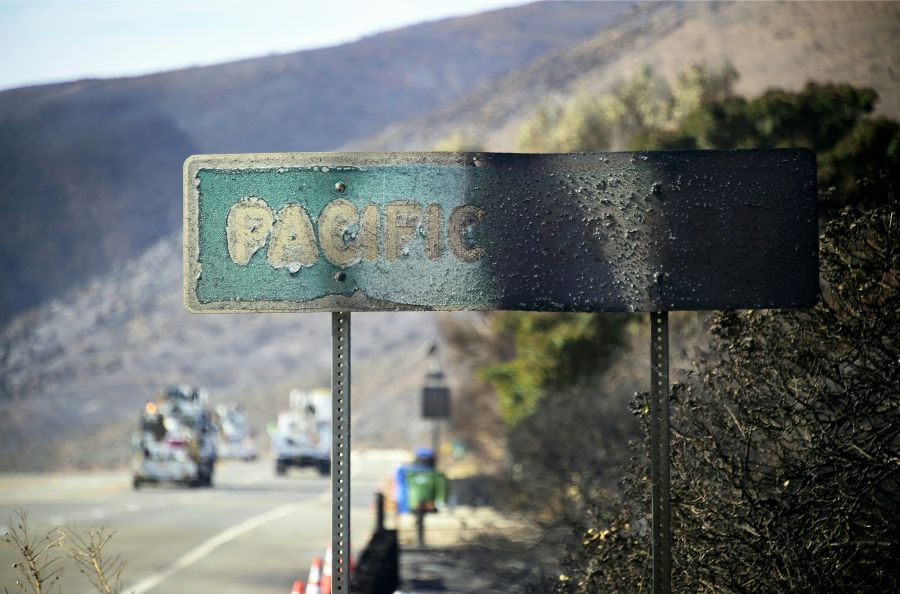 A fire-damaged Pacific Coast sign remains standing along the Pacific Coast Highway amid the blackened and charred hills from the Woolsey Fire in Malibu on Nov. 15, 2018. (Credit: Frederic J. Brown / AFP / Getty Images)