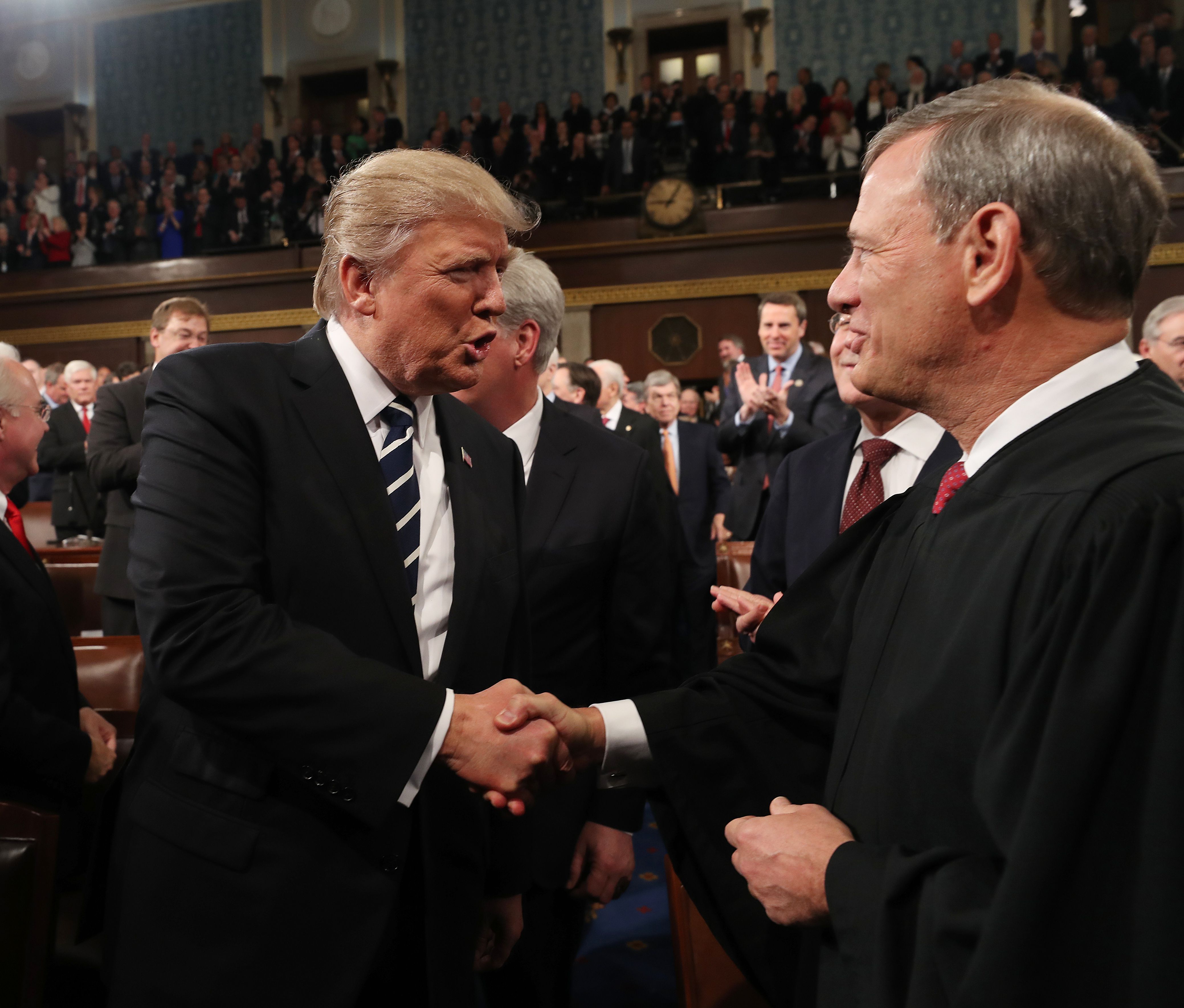 Donald Trump shakes hands with Chief Justice John Roberts as he arrives to deliver his first address to a joint session of Congress from the floor of the House of Representatives in Washington, D.C. on Feb., 28, 2017. (Credit: JIM LO SCALZO/AFP/Getty Images)