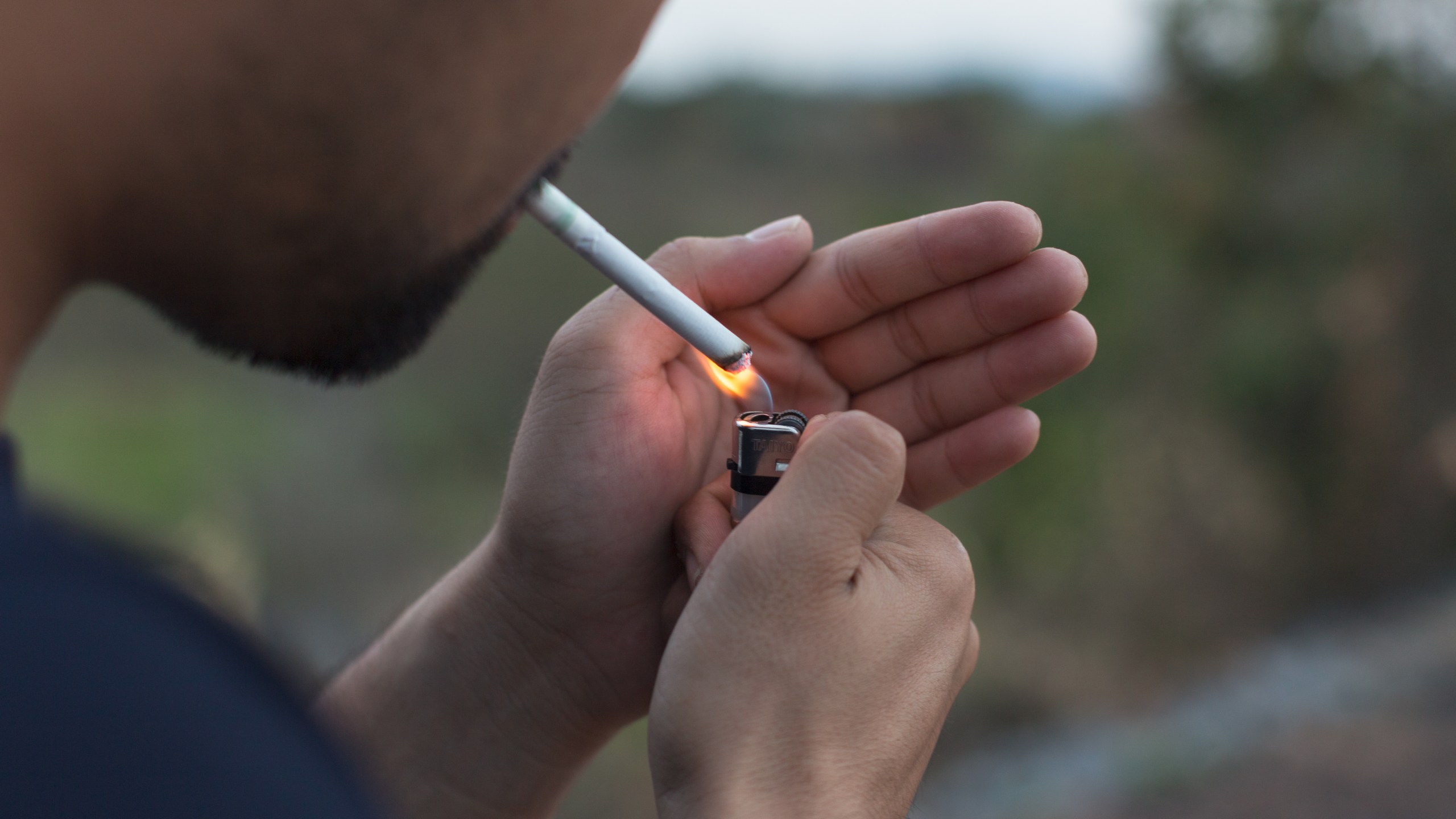 A man is seen lighting a cigarette in this file photo. (Credit: iStock/Getty Images Plus)