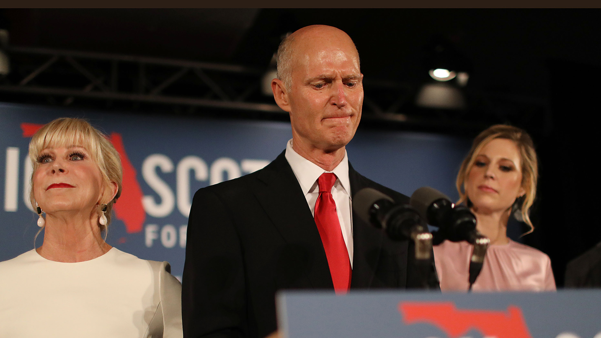 Florida Gov. Rick Scott pauses as he becomes emotional while speaking as he stands with his wife, Ann Scott, left, and daughter Alison Guimard, right, during his election night party at the LaPlaya Beach & Golf Resort on Nov. 6, 2018 in Naples, Florida. (Credit: Joe Raedle/Getty Images)