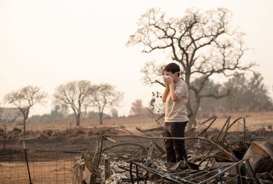 Jeremie Saylors, 11, adjusts his face mask while searching through the burned remains of his home in Paradise on Nov. 18, 2018. (Credit: Josh Edelson / AFP / Getty Images)