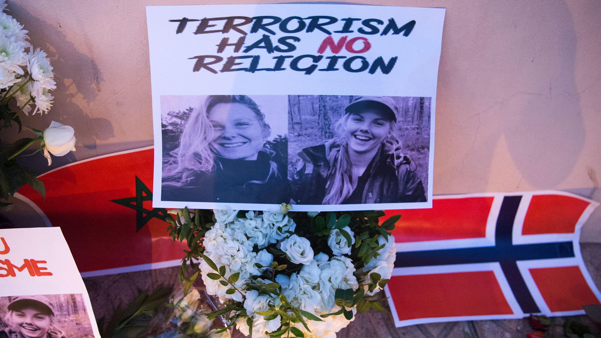 This picture taken on Dec. 21, 2018 shows photos of murdered Danish student Louisa Vesterager Jespersen on the Left and Nowegian Maren Ueland on the right, placed on top of flowers and between the flags of Morocco an Norway as Moroccans pay tribute to the Scandinavian victims. (Credit: Fadel Senna/AFP/Getty Images)