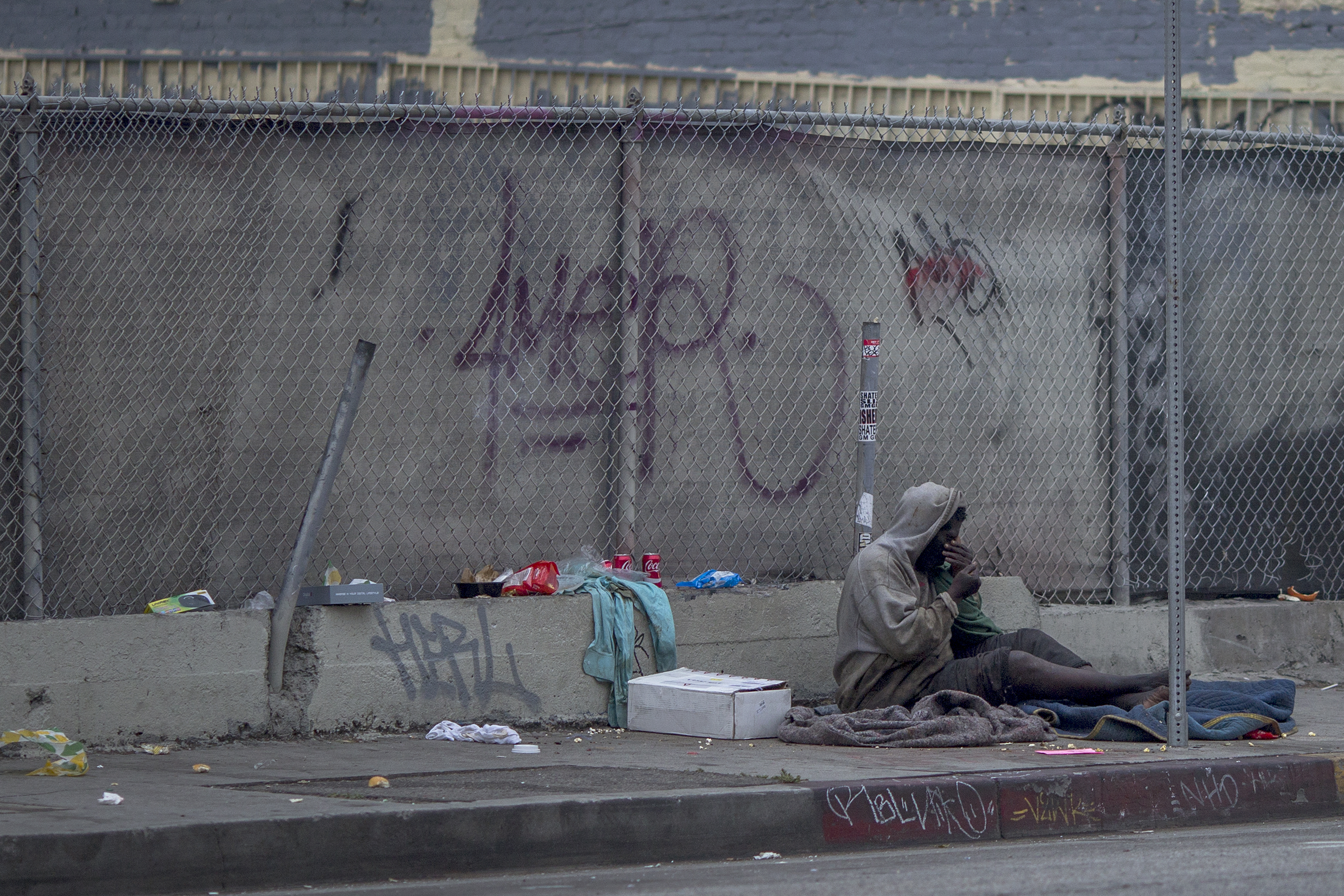 A homeless man sits on a downtown sidewalk where he had slept on May 1, 2017 in Los Angeles, California. (Credit: David McNew/Getty Images)