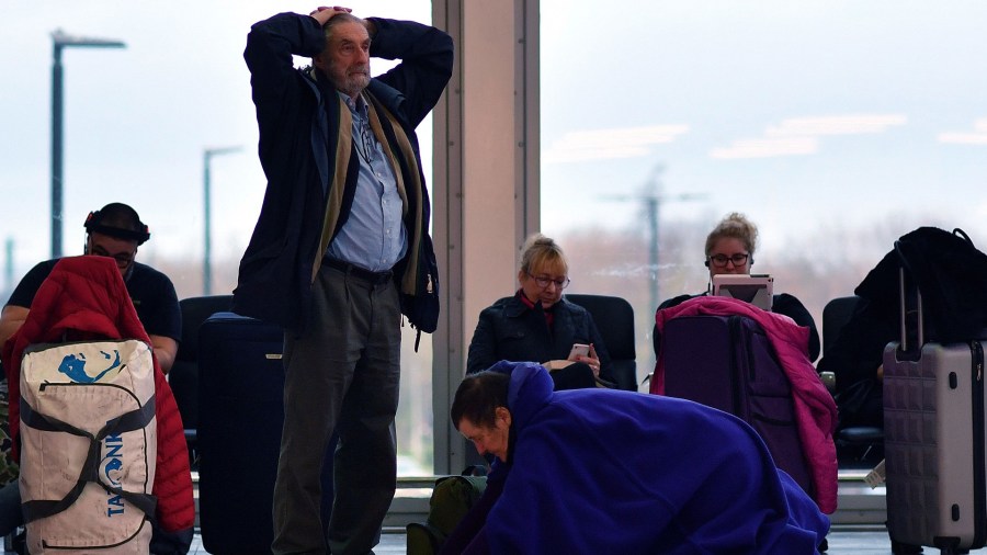 A passenger rolls away a sleeping aid as she sits with their luggage in the South Terminal building at London Gatwick Airport, south of London, on December 21, 2018, as flights started to resume following the closing of the airfield due to a drones flying. - British police were Friday considering shooting down the drone that has grounded flights and caused chaos at London's Gatwick Airport, with passengers set to face a third day of disruption. Police said it was a "tactical option" after more than 50 sightings of the device near the airfield since Wednesday night when the runway was first closed. (Credit: Ben STANSALL / AFP/Getty Images)