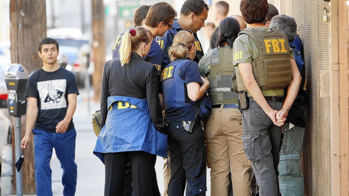 In this undated photo, FBI agents huddle in the 700 block of East Pico Boulevard as a series of raids are carried out in downtown L.A.'s Fashion District. (Credit: Al Seib, Los Angeles Times)