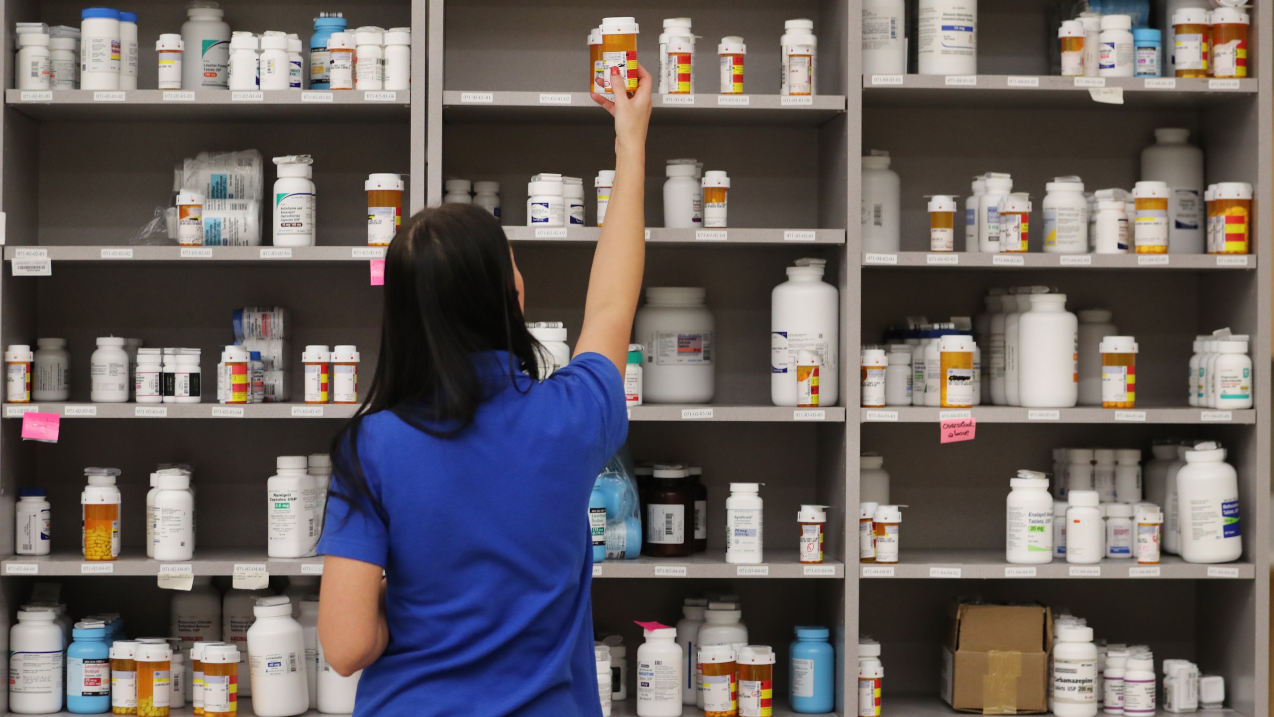 A pharmacy technician grabs a bottle of medication off a shelf on Sept. 10, 2018 in Midvale, Utah. (Credit: George Frey/Getty Images)