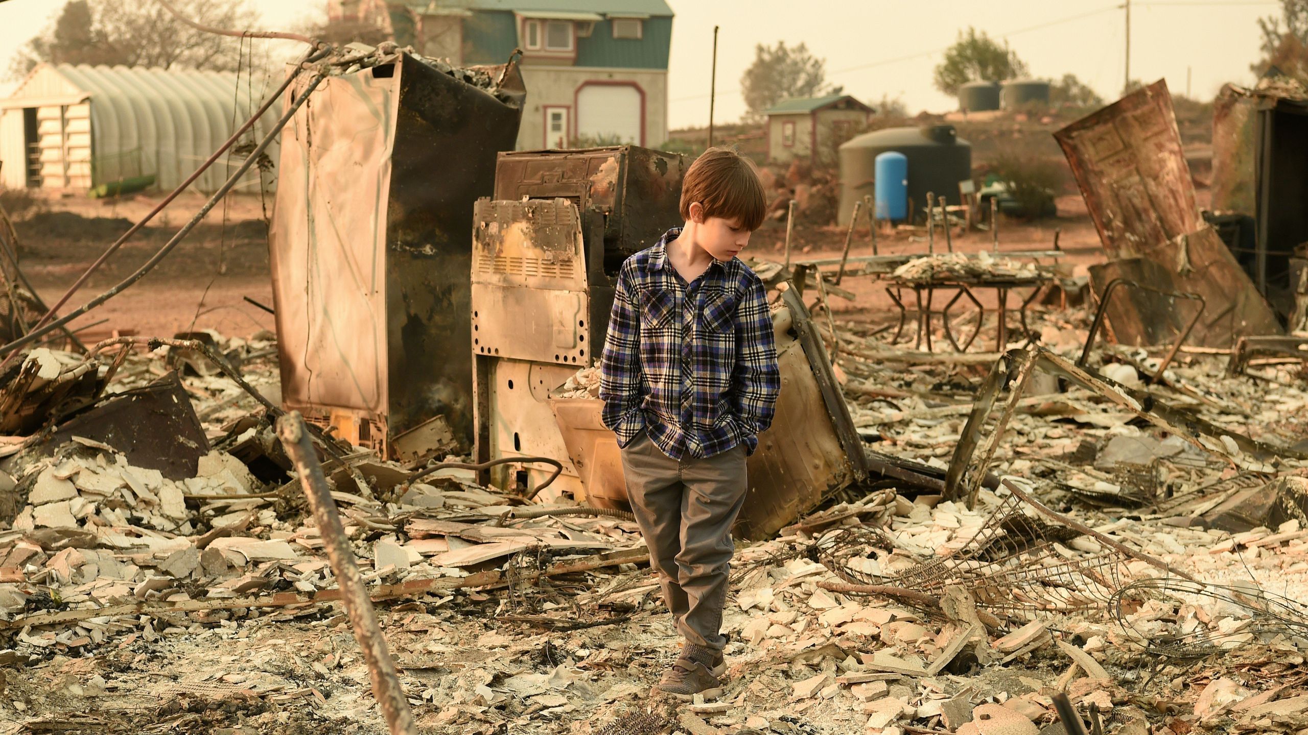 Jacob Saylors, 11, walks through the burned remains of his home in Paradise, Calif. on Nov. 18, 2018. The family lost a home in the same spot to a fire 10 years prior. (Credit: Josh Edelson / AFP) require. (Credit: JOSH EDELSON/AFP/Getty Images)