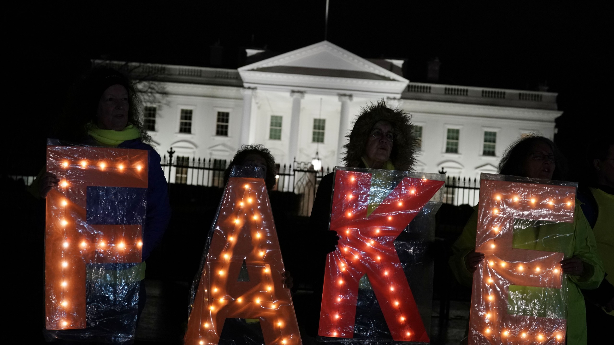 Activists hold a lit "FAKE" sign as they stage a protest outside the White House in response to U.S. President Donald Trump’s prime-time address to the nation on Jan. 8, 2019. (Credit: Alex Wong / Getty Images)