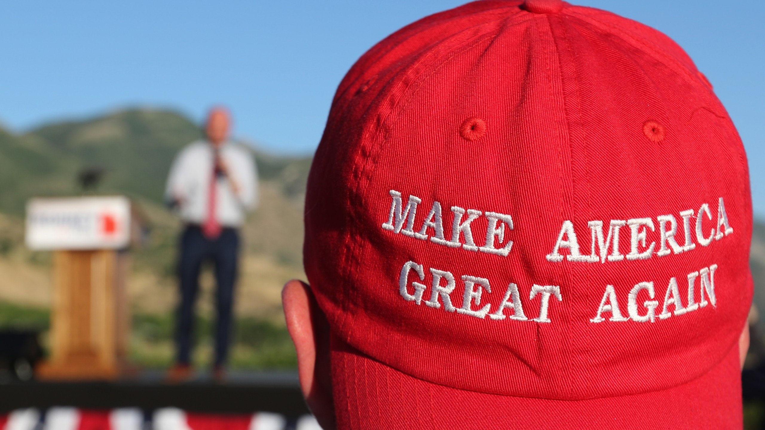 A Romney supporter listens to a speaker as he wears a "Make America Great Again" hat at the Mitt Romney election party on June 26, 2018 in Orem, Utah. (Photo by George Frey/Getty Images)