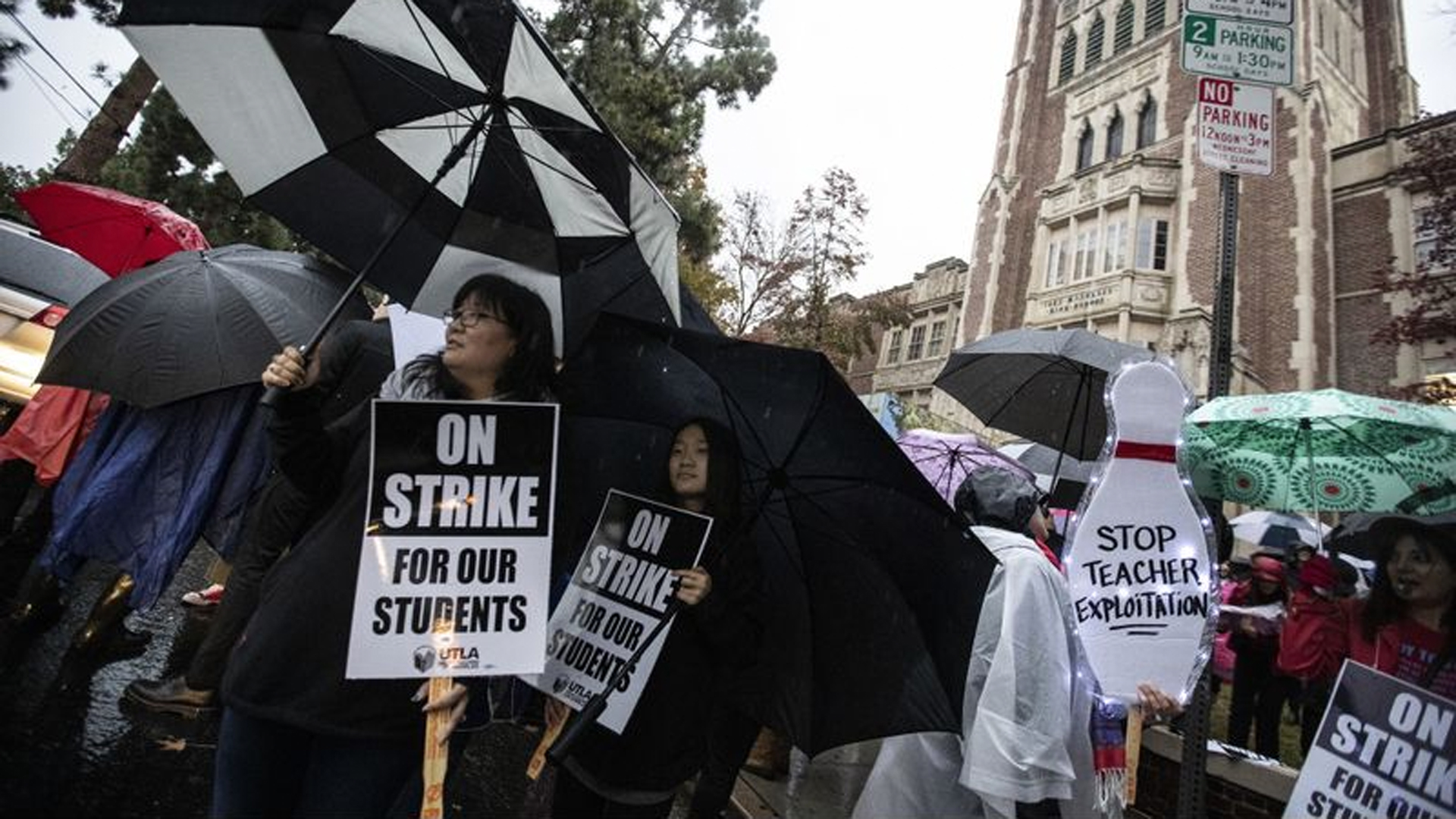 English magnet teacher Sarah Lee-Park, left, is among those holding signs and umbrellas at John Marshall High School on Monday morning. Her daughter Faith Park, 13, joined her on the picket line. (Credit: Brian van der Brug / Los Angeles Times)