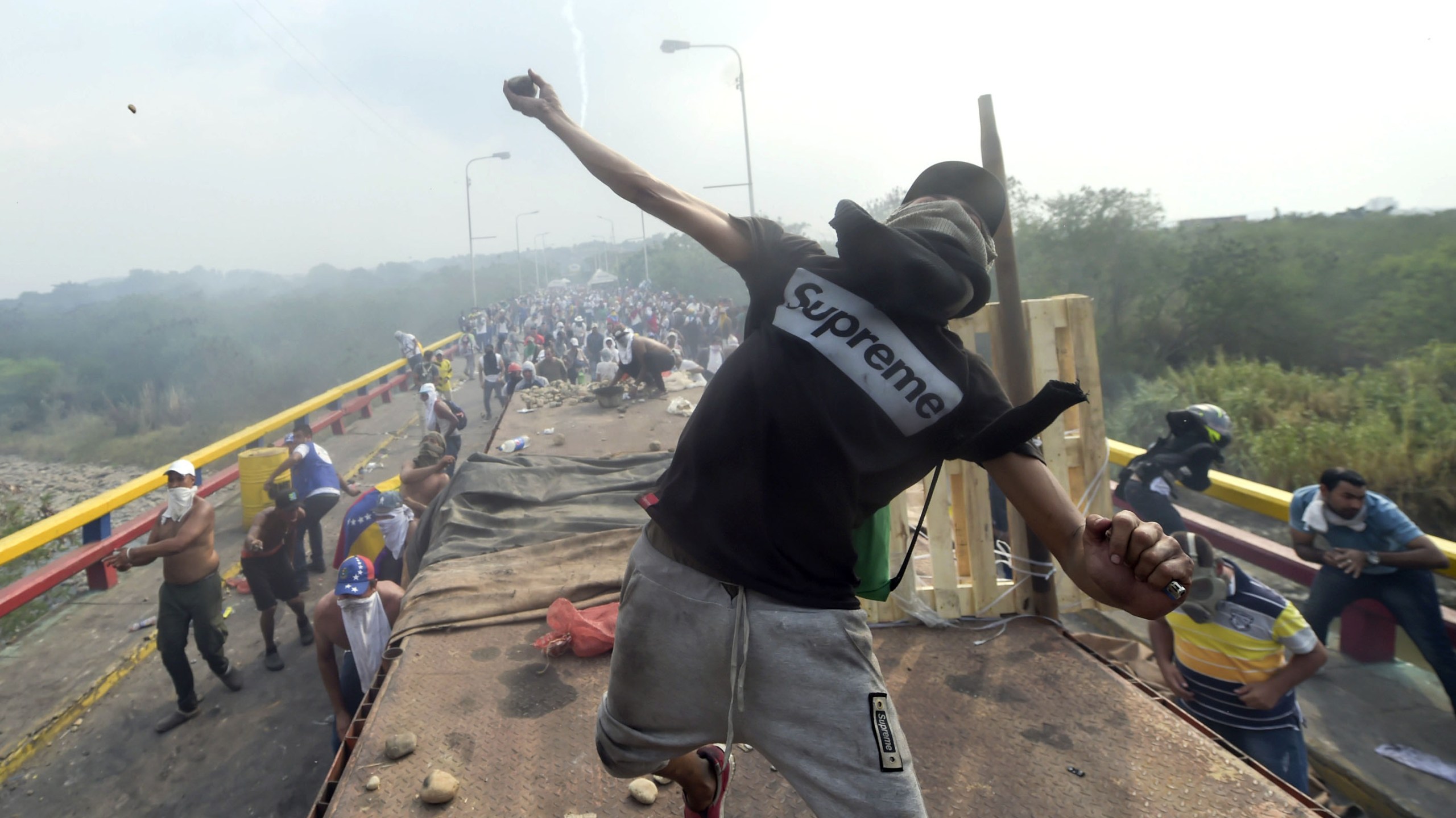 Demonstrators throw stones in clashes with the security forces at the Francisco de Paula Santander international bridge Bridge linking Cucuta, Colombia, and Urena, Venezuela, during an attempt to cross humanitarian aid over the border into Venezuela, on Feb. 23, 2019. (Credit: RAUL ARBOLEDA/AFP/Getty Images)