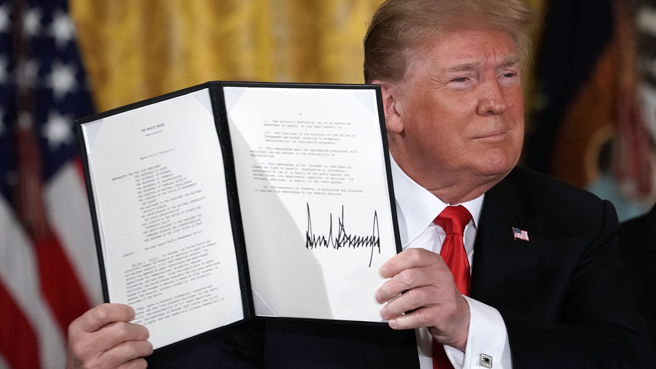 Donald Trump holds up an executive order that he signed during a meeting of the National Space Council at the East Room of the White House June 18, 2018 in Washington, D.C. (Credit: Alex Wong/Getty Images)